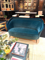 An original Italian 1950s two seater sofa with curved back, with brass and wooden feet