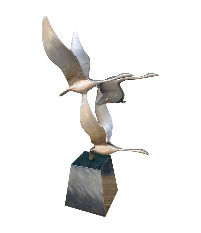 A French 1960s Mid century bronze sculpture by Lumiere of three flying swans mounted on a bronze base,