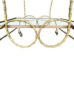 A pretty French 1950s solid brass faux bamboo bar trolley by Maison Baques with two glass shelves