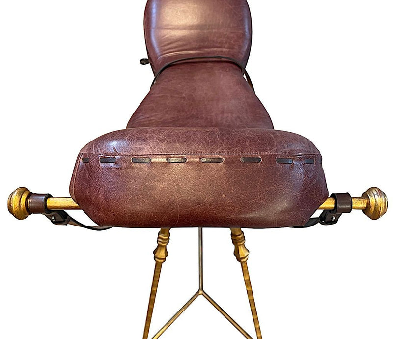 A Mark Brazier Jones "Tally Ho" chair a sculptural chair upholstered in a tan leather, with leather reigns, straps and steel stirrups on a stylised gilt wrought iron frame